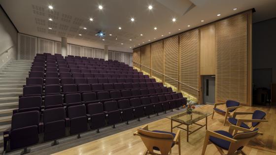 Purple seats in a conference centre, seen from the stage. Coffee table in foreground