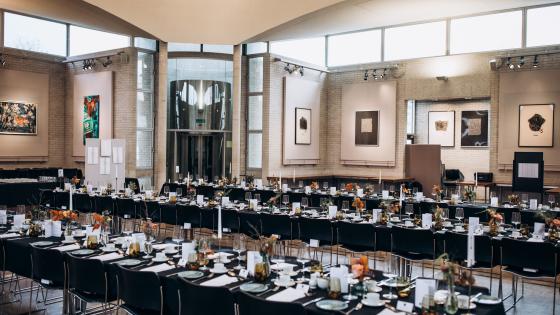 Rows of banqueting tables with black table cloths in Dome Dining Hall. Artwork in the background.
